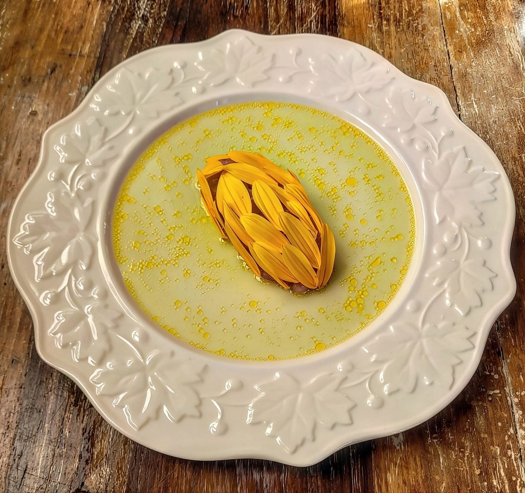 "Portami il girasole ch'io lo trapianti
nel mio terreno bruciato dal salino,
e mostri tutto il giorno agli azzurri specchianti
del cielo l'ansietà del suo volto giallino.

Tendono alla chiarità le cose oscure,
si esauriscono i corpi in un fluire
di tinte: queste in musiche. Svanire
è dunque la ventura delle venture.

Portami tu la pianta che conduce
dove sorgono bionde trasparenze
e vapora la vita quale essenza;
portami il girasole impazzito di luce."
Nel mese di ottobre sbocciano i topinambur che con i loro fiori gialli ci ricordano i girasoli,l'estate passata e ci danno la consapevolezza del tempo che fluisce.
 Petali di topinambur, tartare di tonno. Intorno, l'acqua viva del sedano fresco, la scossa acerba del limone verde e la nota calda dello zenzero. 
È questo l'autunno che cerca la sua trasparenza.