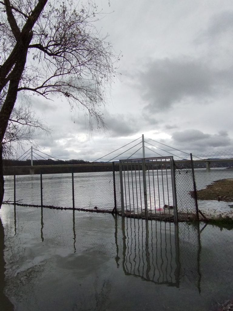 cercare la tranquillità vicino al fiume, davanti ad un cancello chiuso ed un ponte che unisce.