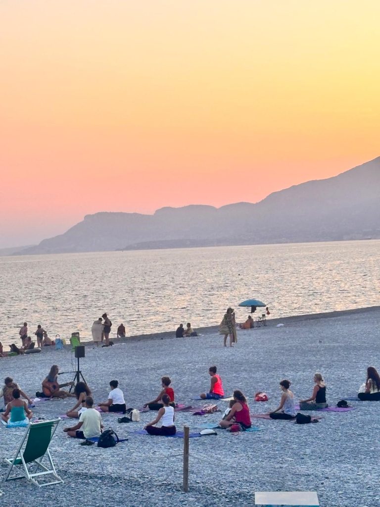 Praticare yoga in riva al mare mentre la giornata volge al termine e dolcemente arriva la sera