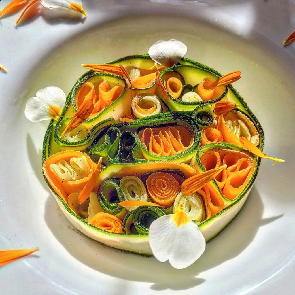 Creare piatti con i colori della natura. 
Verdure crude e dettagli floreali. 
Un mosaico di nastri di zucchine, carote e  gambi di carciofo. Pochi sapori essenziali: olio, sale, limone e pepe verde per risvegliare i sapori.
La dolcezza della primula e la vivacità della calendula annunciano la primavera. Non è solo un antipasto, è il mio modo di volermi bene.