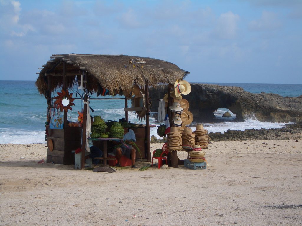 guardare l'orizzonte e ammirare incantata una bancarella improvvisata sulla sabbia bianca con tanti cappelli di paglia che fanno subito vacanza